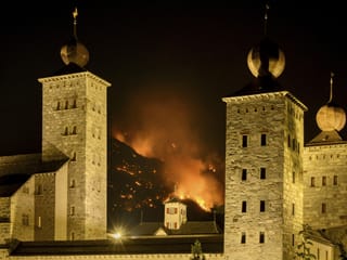 View of Stockalper Castle at night.  Flames on the mountain can be seen in the background.
