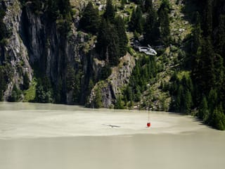 A helicopter hovers over a reservoir with a water bag.