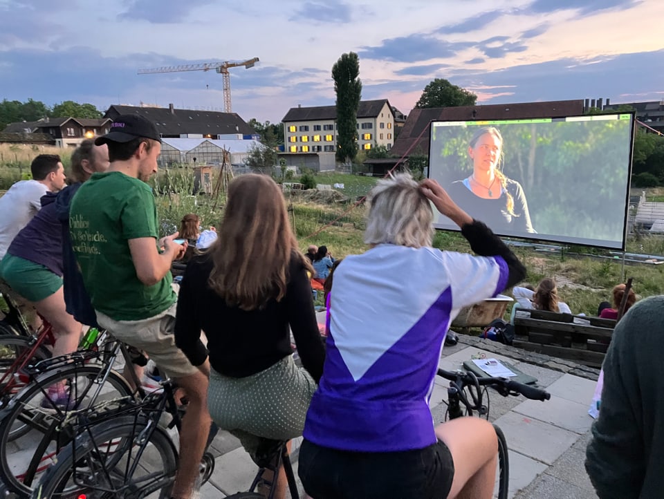 Five cinema-goers pedal on their bikes and watch the film on the screen