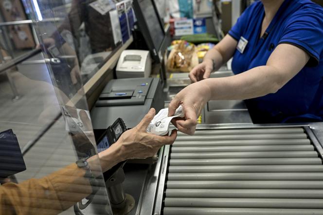 A cashier gives a customer her receipt after payment in a supermarket in Lyon, July 25, 2023.