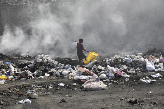 A woman walks through a landfill in search of salvageable items, in Haiti's capital Port-au-Prince, July 1, 2023.