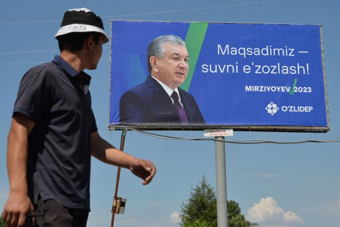 A person walks past a campaign billboard of Uzbekistan's incumbent president and presidential candidate Shavkat Mirzioev in Krasnogorsk, about 60 kilometers from Tashkent, on July 8, 2023.