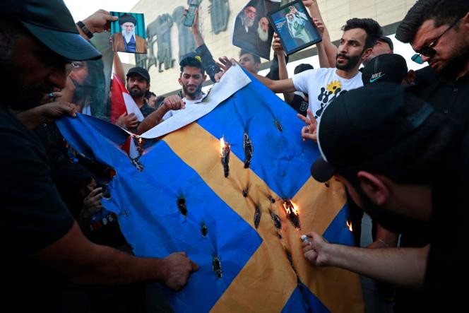 Protesters burn a Swedish flag in Tahrir Square in Baghdad following the trampling of the Koran in Stockholm on July 20, 2023.