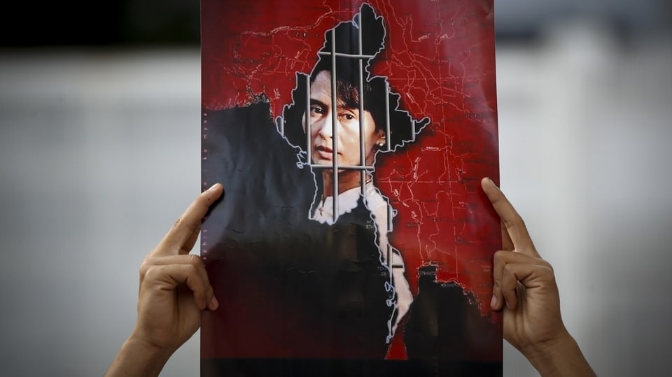 Man holding up picture of Aung San Suu Kyi