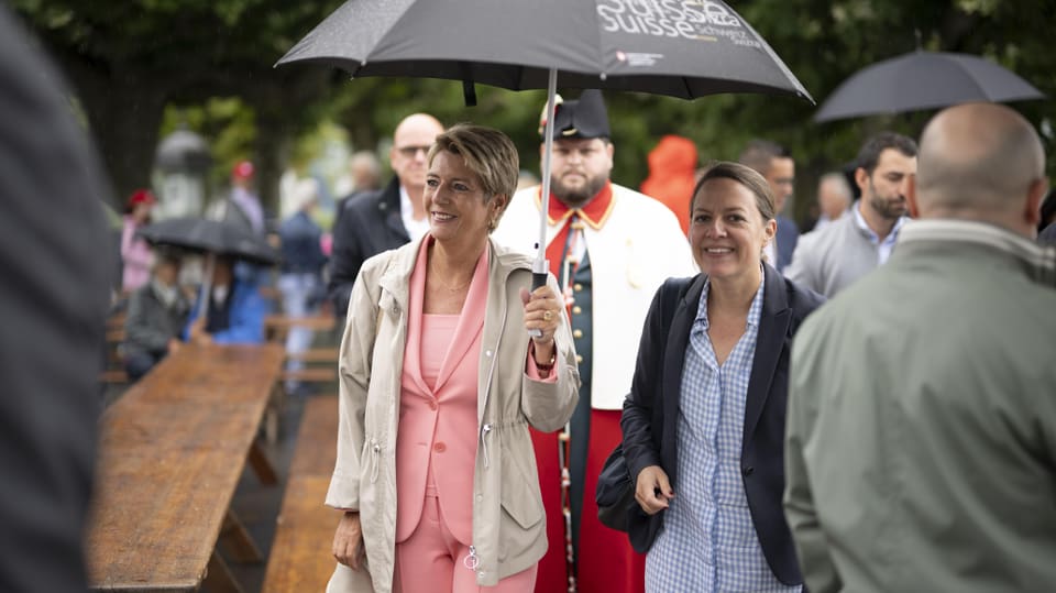 Karin-Keller-Sutter with an umbrella and a smile on her face