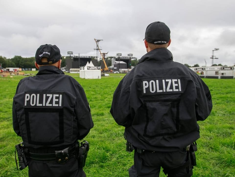 Two police officers photographed from behind on the festival grounds