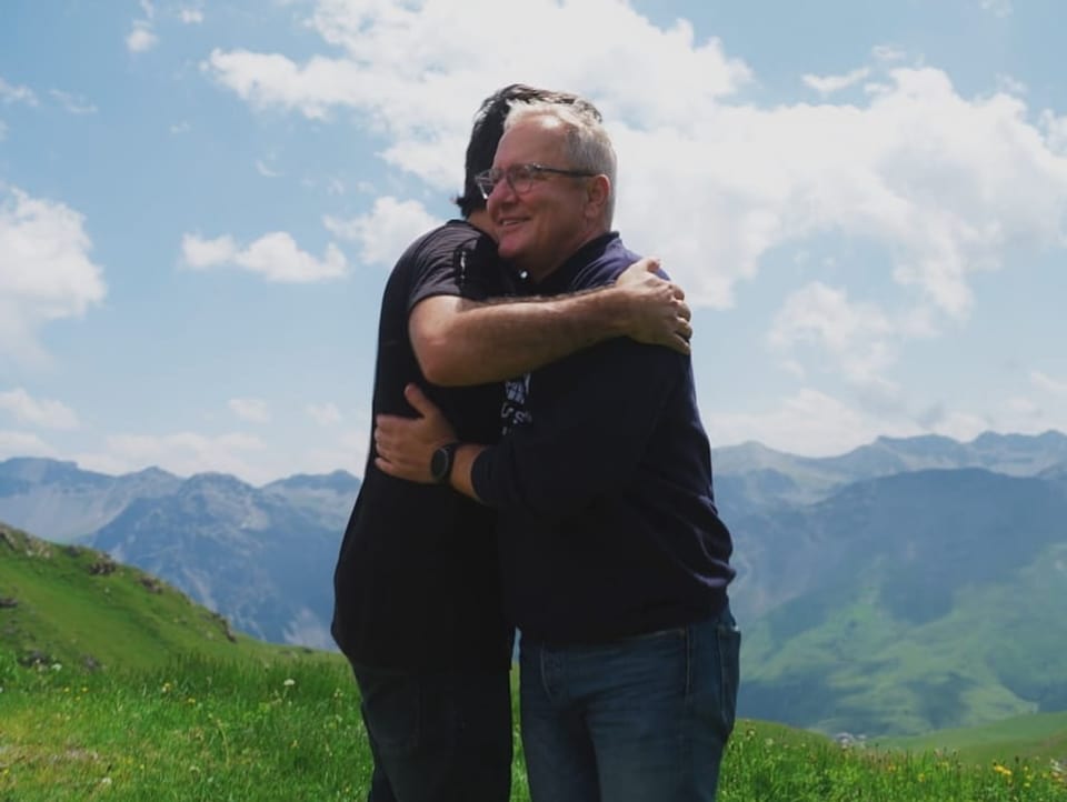 Cenk and Frank Baumann hug in the mountains 