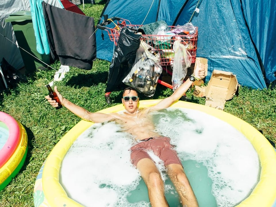 Man bathes in a small inflatable pool with foam