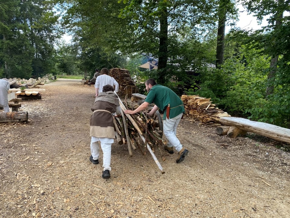 Three men are pulling a cart full of wood