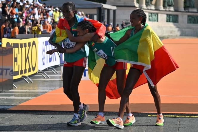 Ethiopian gold medalist Amane Beriso Shankule (left) and silver medalist Gotytom Gebreslase (right) help their compatriot Yalemzerf Yehualaw after the women's marathon at the World Championships in Athletics in Budapest, August 26, 2023. 