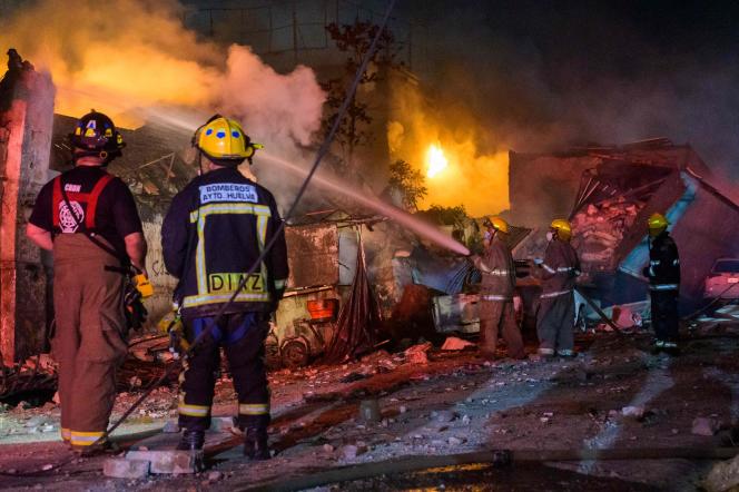 Firefighters work to put out a fire after an explosion at a commercial establishment in San Cristobal, Dominican Republic, August 14, 2023.