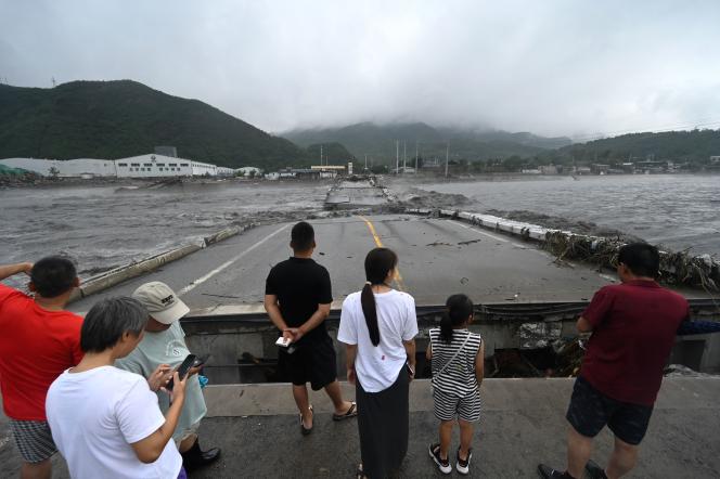Residents of Beijing's Fangshan district stand in front of a washed-out bridge on August 1, 2023.