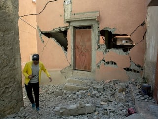 A man walks past a destroyed building.