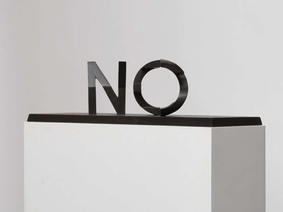 Black lettering sculpture “No” on a white base, white background
