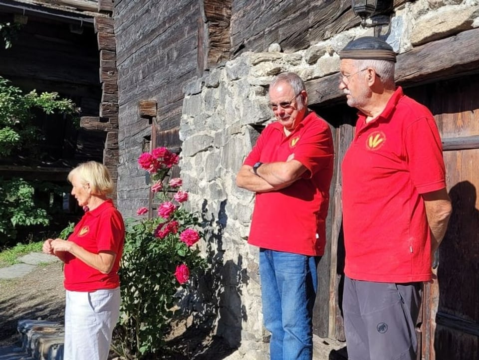 Committee stands in front of the wooden door of the stone house.