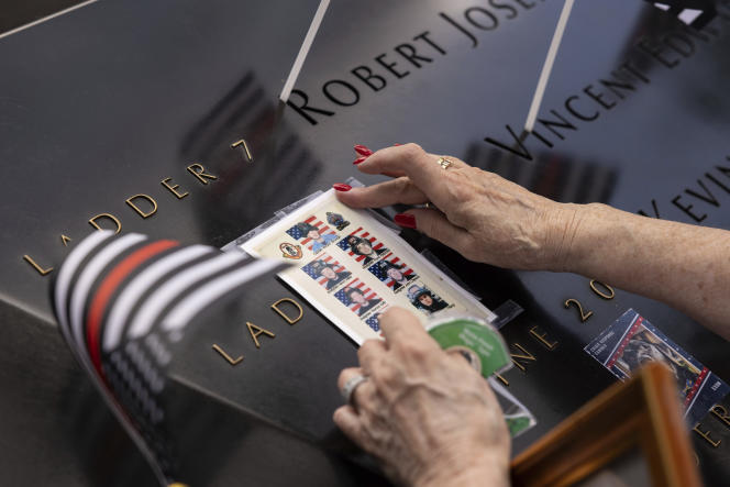 A person places photos of fallen firefighters on the 9/11 Memorial during the commemoration ceremony for the twenty-second anniversary of the terrorist attacks of September 11, 2001, Monday, September 11, 2023, in New York. 