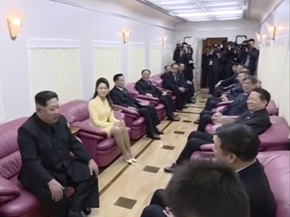 Kim on the train with people on pink chairs