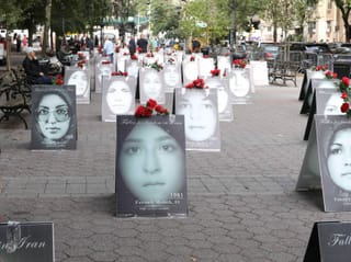 There are billboards on the floor with black and white portraits of women and red flowers