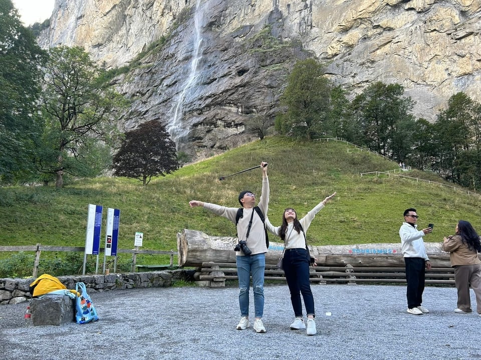 People take photos of themselves in front of a waterfall