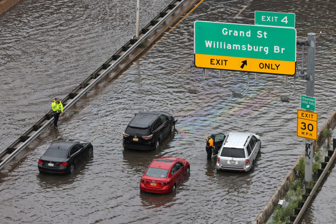 Police officers help stranded motorists on a flooded street in Manhattan near the Williamsburg Bridge in New York on September 29, 2023. 
