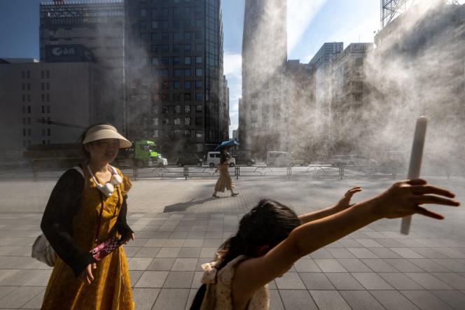People walk past a misting system in Tokyo's Ginza district on July 10, 2023.
