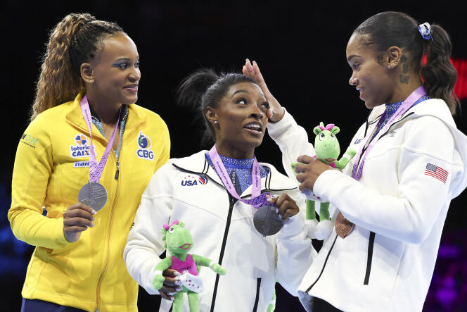Simone Biles surrounded by Rebeca Andrade (left) and Shilese Jones, on the world podium in Antwerp, Belgium, October 6, 2023.