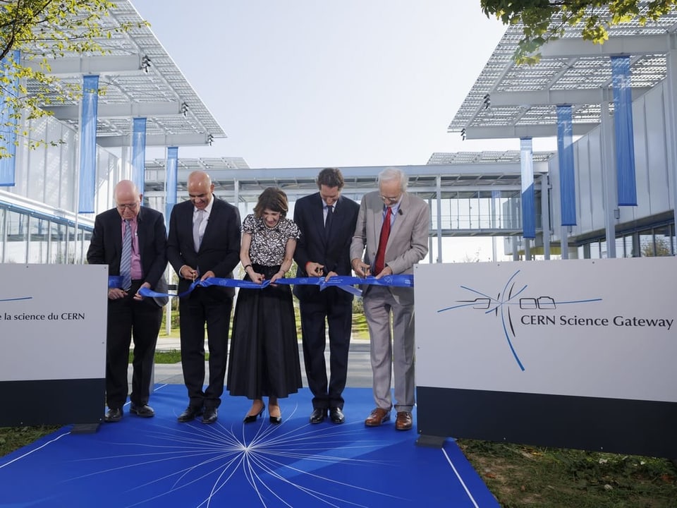 Five people cut a ribbon at the Cern visitor center.
