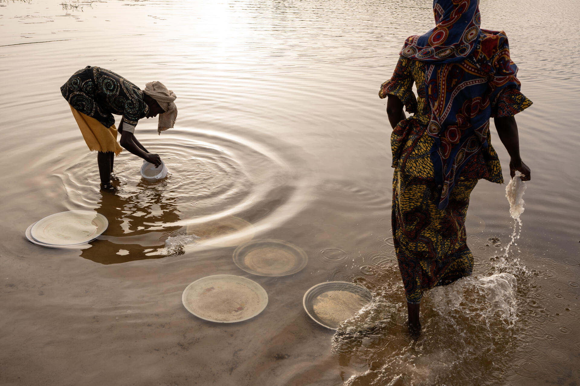 Harmata Hassan, 12, and Morom Mama wash dishes in Lake Chad, Baga Sola, April 1, 2023.