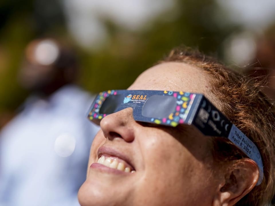 A woman looks at the sky with special glasses.
