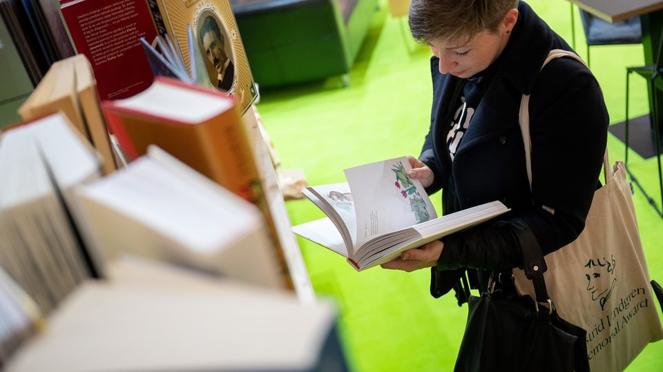 Woman stands in a trade fair stand and leafs through a book