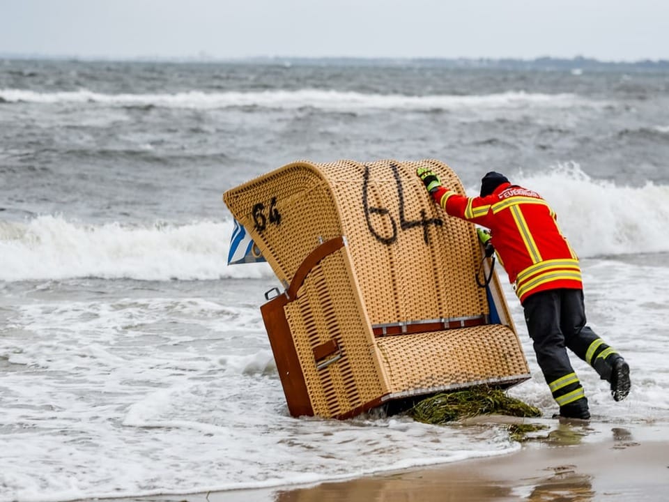 Firefighter tries to get a chair out of the sea.