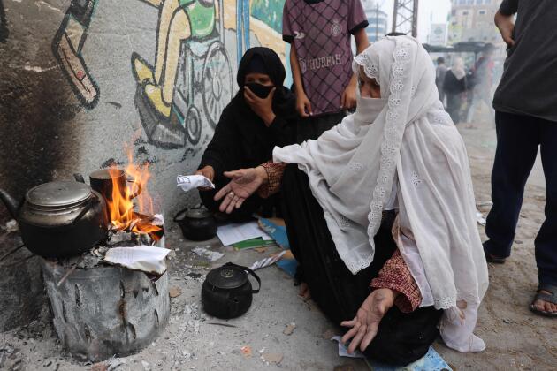 Women burn paper to heat tea water, in Rafah, southern Gaza Strip, October 28, 2023.