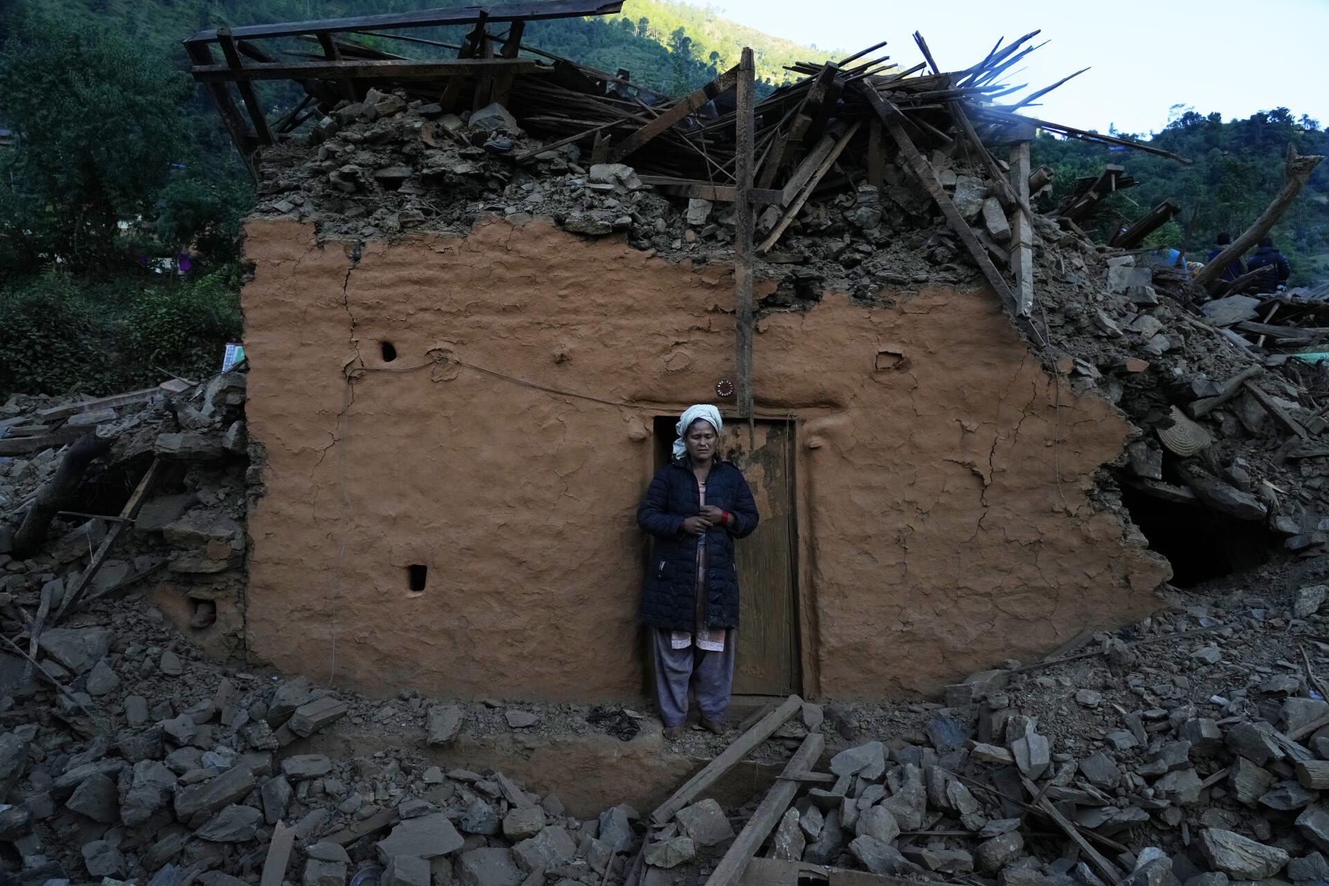 A woman in front of an earthquake-damaged house in Jajarkot district, northwest Nepal, Sunday, November 5, 2023.