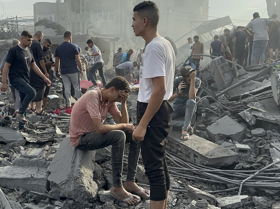 Two young men in the rubble of a destroyed house.