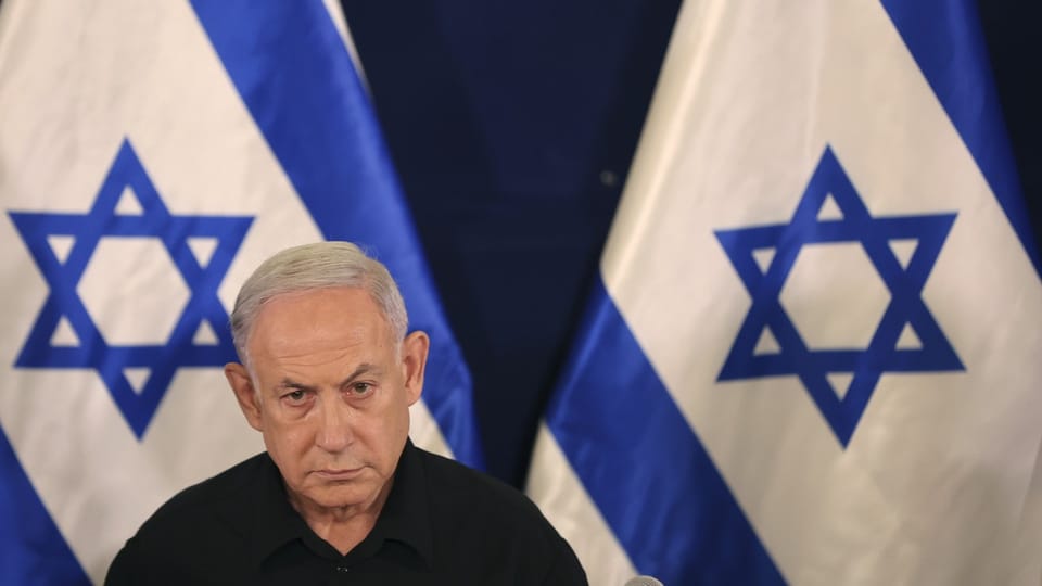 Netanyahu in front of Israeli flags.