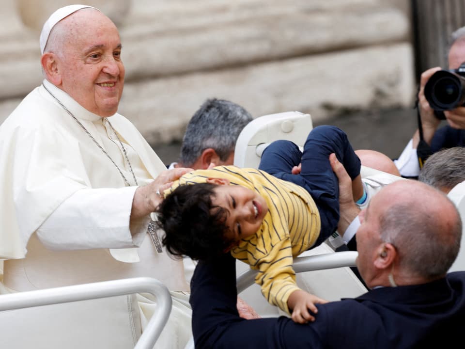 Ein Mann trägt ein Kind von Papst Franziskus weg.