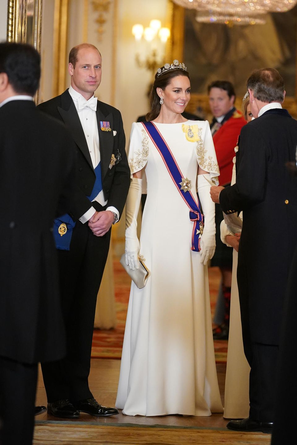 Kate shines alongside Prince William in a white cape robe at the state banquet at Buckungham Palace. 