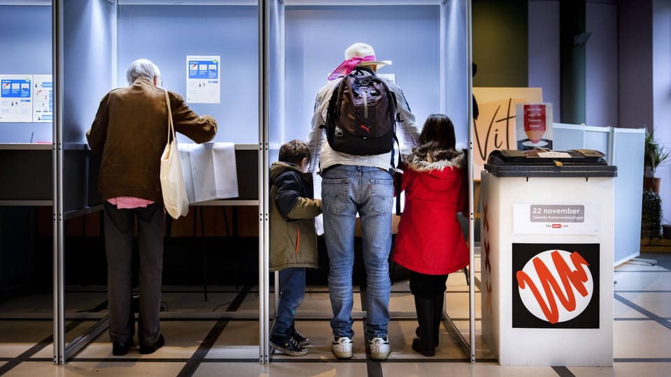 An adult stands in a polling office and votes.  His two children are on the left and right.