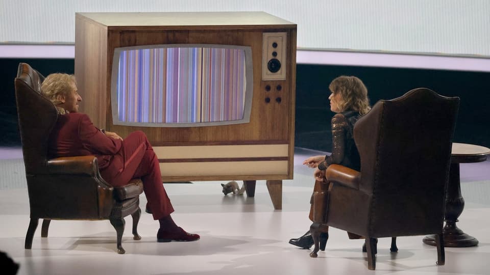 Thomas Gottschalk and Julia Reichelt sit in front of a television that shows colored barcodes.