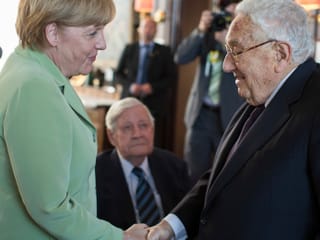 Angela Merkel shakes hands with Henry Kissinger