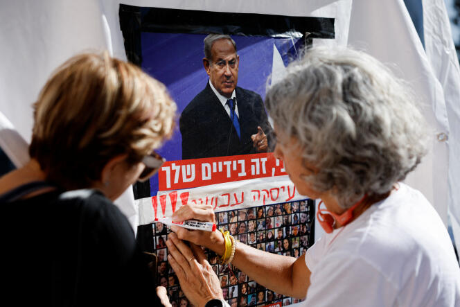 A woman writes “it’s in your hands” on a poster depicting Israeli Prime Minister Benjamin Netanyahu and photos of hostages held in the Gaza Strip, in Tel Aviv (Israel) on November 21, 2023.