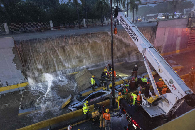 Rescuers try to free vehicles trapped under a wall that collapsed on an avenue, at the entrance to a tunnel, in Santo Domingo, November 18, 2023. 