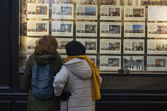 Two women look at the advertisements of a real estate agency, in Paris, March 1, 2022.
