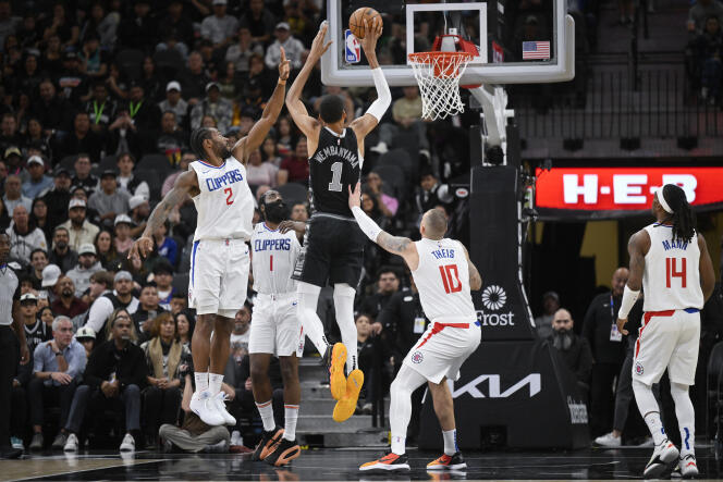 Victor Wembanyama, dressed in the black San Antonio Spurs jersey, in the middle of the Los Angeles Clippers defense.  November 22, 2023 in Texas. 