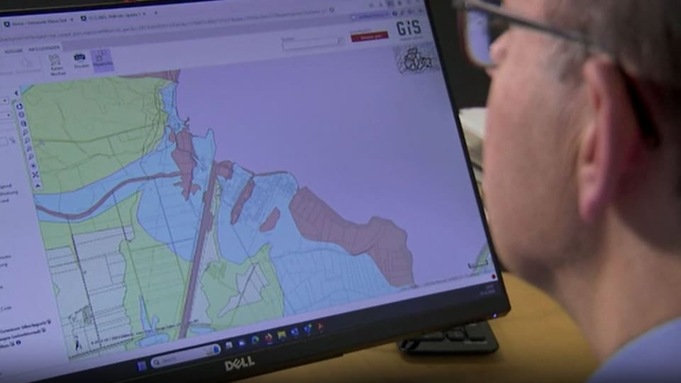 A man with glasses looks at a computer map of Sachseln.