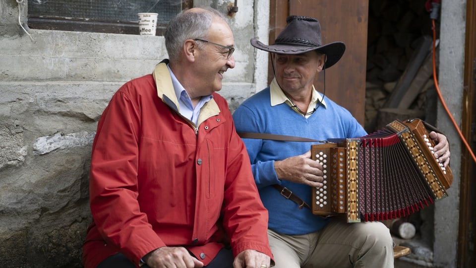 Parmelin sits next to an accordion player.