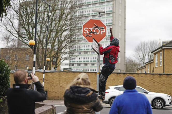 A man removes a barely claimed and unveiled Banksy artwork from the intersection of Southampton Way and Commercial Way in Peckham, south-east London, on December 22, 2023, in front of witnesses filming the scene. 