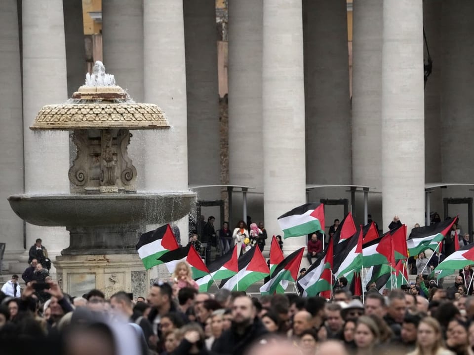 People hold up Palestinian flags in St. Peter's Square