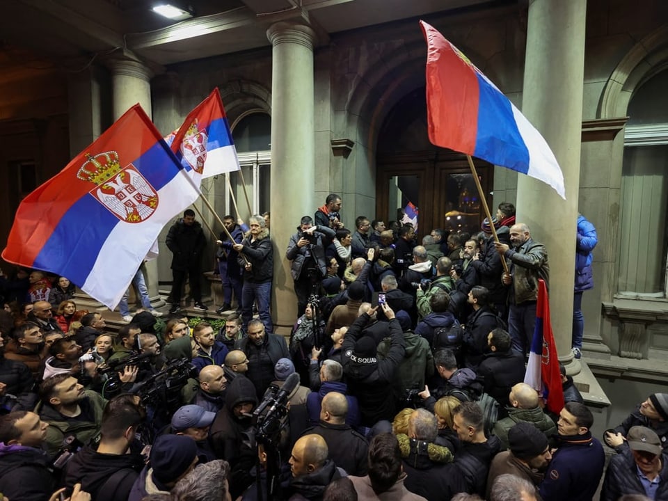 People protest with Serbian flags in front of the town hall in Belgrade.