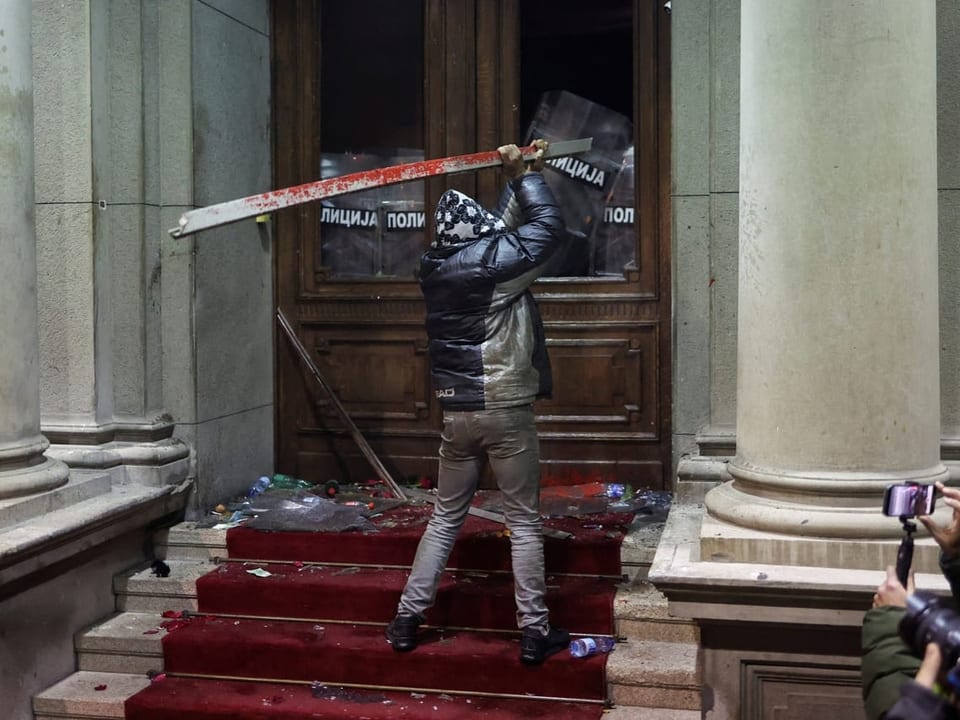 A man hits the entrance to Belgrade City Hall with a metal bar.